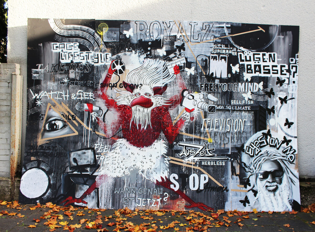 Graffiti-Leinwand in Köln zeigt eine dynamische Streetart-Komposition mit Texten wie 'CAGE LIFESTYLE', 'ROYALZ' und 'FREE YOUR MIND'. Ein stilisierter Affe mit Kamera-Elementen und Motive wie Schmetterlinge und ein Auge in einem Dreieck stehen im Vordergrund. Die Leinwand ist von herbstlichen Blättern umgeben.